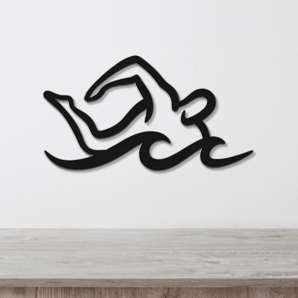 Black metal swimmer wall art with fluid motion cutouts, mounted on a white wall above a light wood counter.