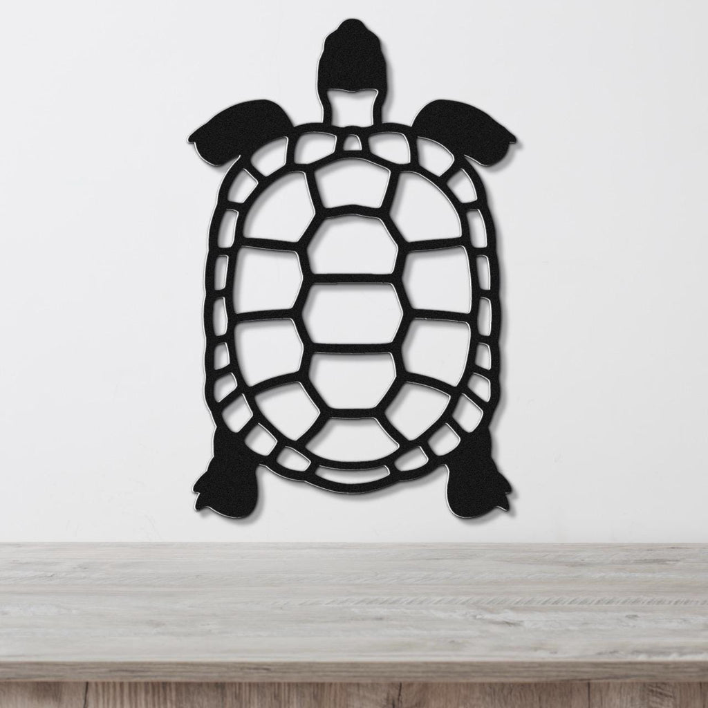 Black metal turtle wall art with a cutout shell design, mounted on a white wall above a light wood surface.