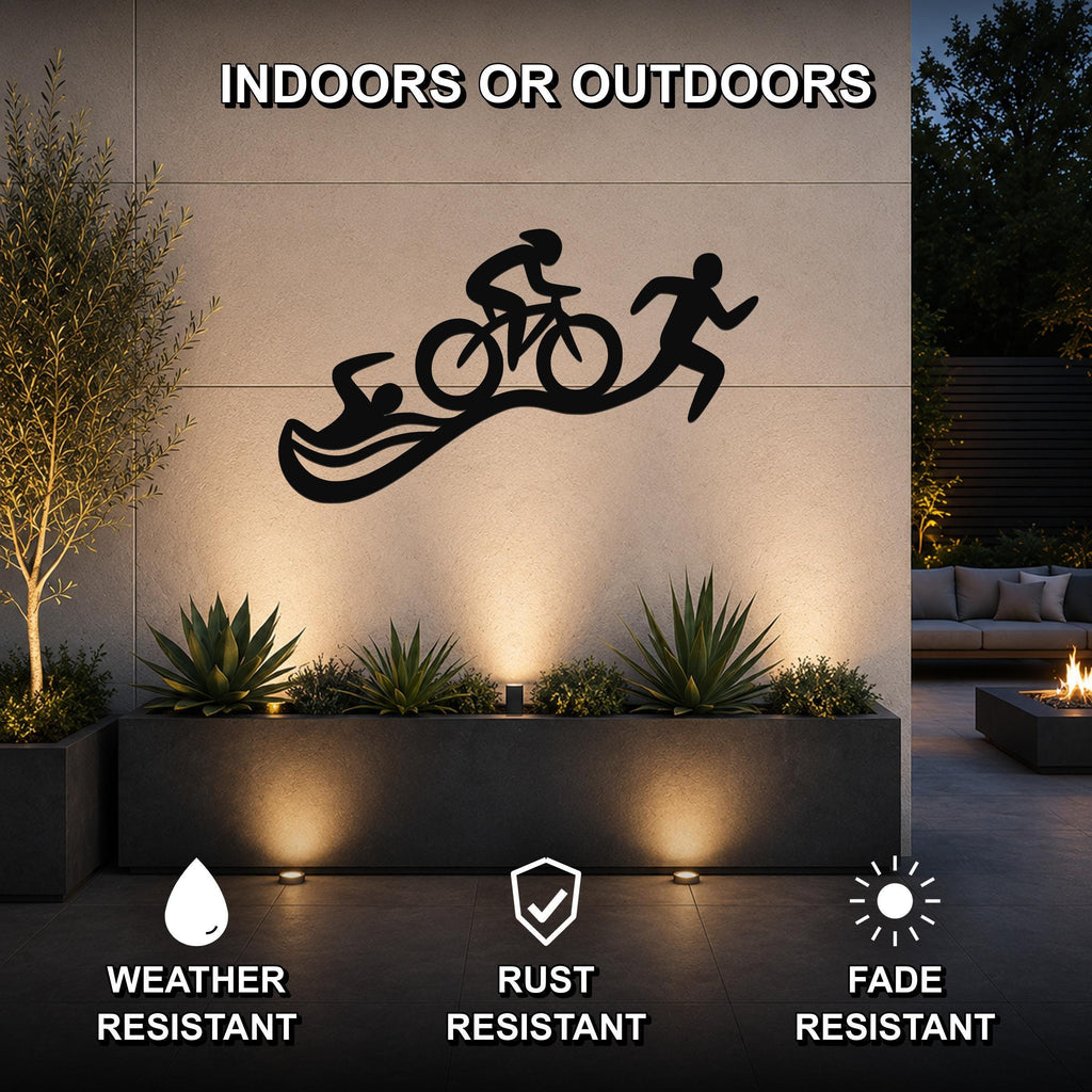 Black metal triathlon wall art with swim, bike, and run silhouettes, mounted on an outdoor wall above a planter in a modern patio setting.