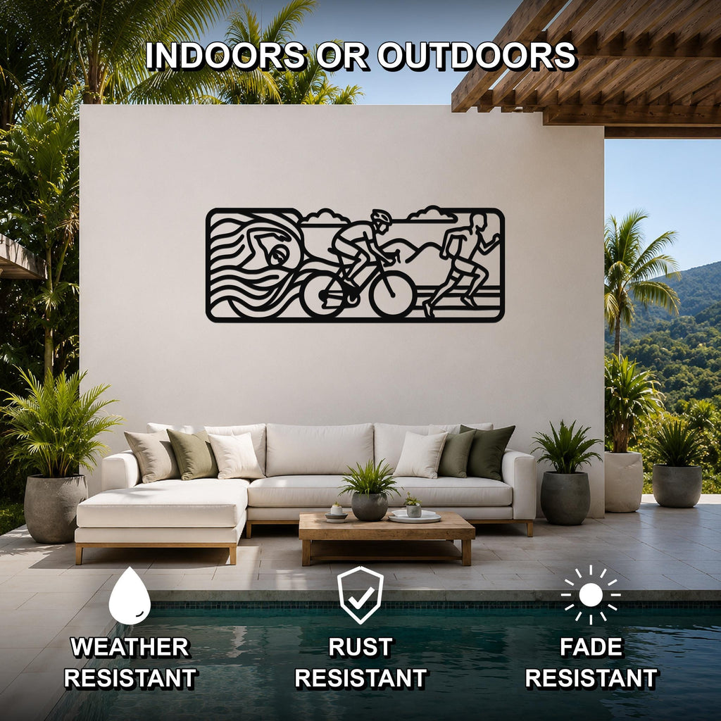 Black metal triathlon wall art with swim, bike, and run silhouettes, mounted on a white outdoor patio wall above a sofa.