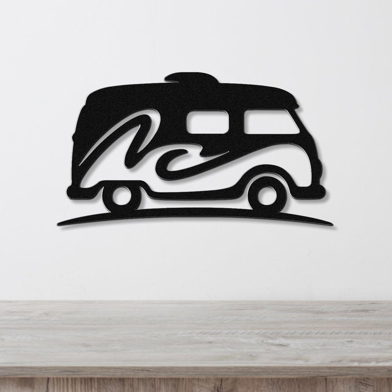 Black metal wall art silhouette of a vintage camper van with a wave design, mounted on a white wall above a wooden surface.