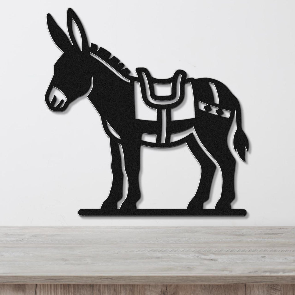 Black metal burro wall art with saddle and bridle cutouts, mounted on a white wall above a wooden surface.