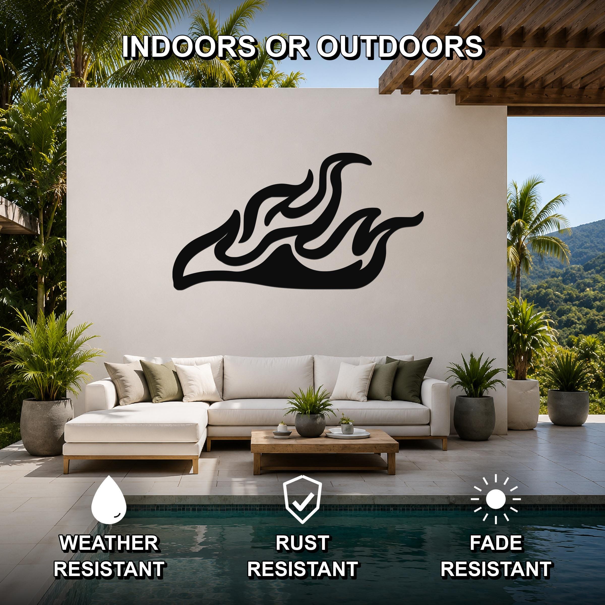 Black metal flame wall art with flowing silhouette cutouts, mounted on a white outdoor wall above a sofa in a patio living area.