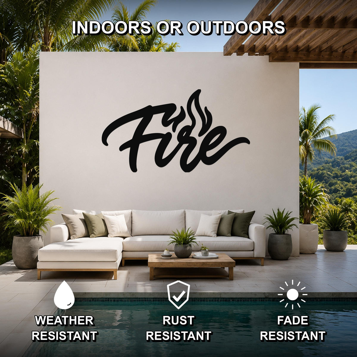 Black metal wall sculpture with the word "Fire" in cursive script and flame cutouts, mounted on a white outdoor wall above a sofa in a patio living area.