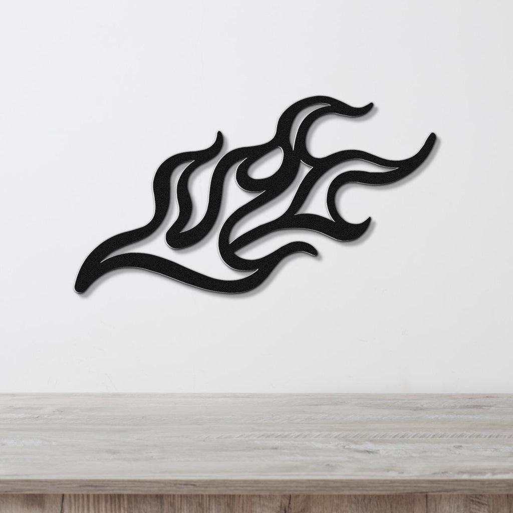 Black metal wall art with a fluid flame design, featuring interwoven curves and cutouts, mounted on a white wall above a light wood surface.