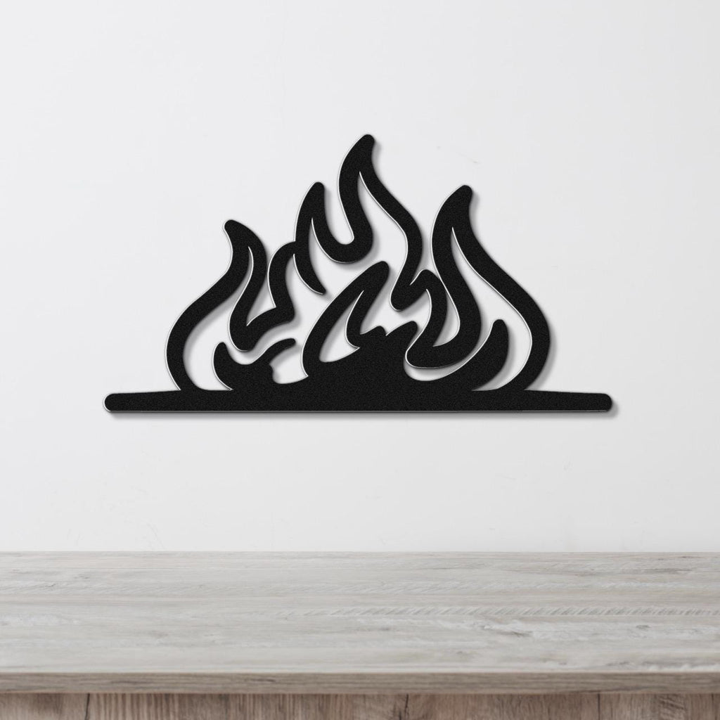 Black metal flame wall art with fluid silhouette cutouts, mounted on a white wall above a light wood surface.