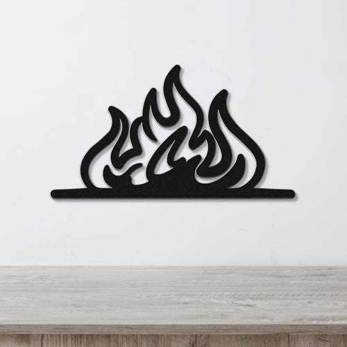 Black metal flame wall art with fluid silhouette cutouts, mounted on a white wall above a light wood surface.
