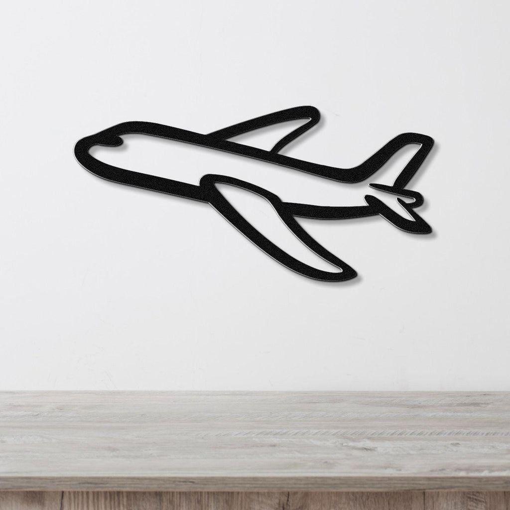Black metal airplane wall art with a bold silhouette design, mounted on a white wall above a light wood surface.