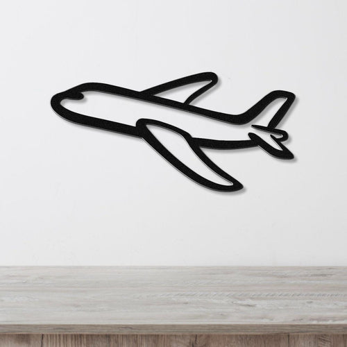 Black metal airplane wall art with a bold silhouette design, mounted on a white wall above a light wood surface.