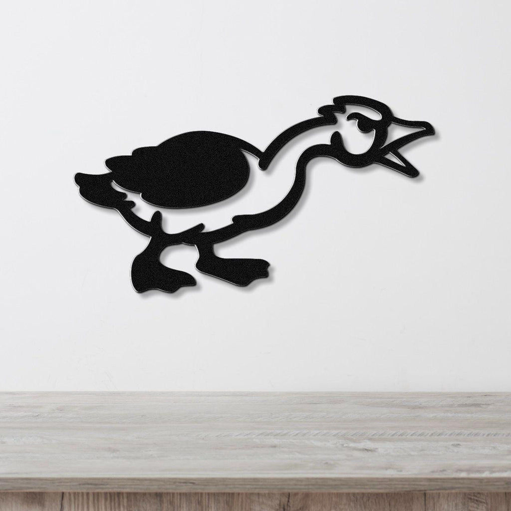 Black metal wall art silhouette of a goose in motion, mounted on a white wall above a light wood surface.