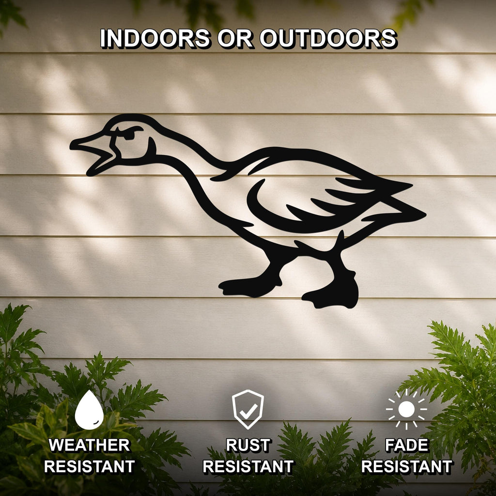 Black metal goose wall art silhouette with an angry expression, mounted on a beige outdoor wall with green plants below, weather resistant, rust resistant, and fade resistant.