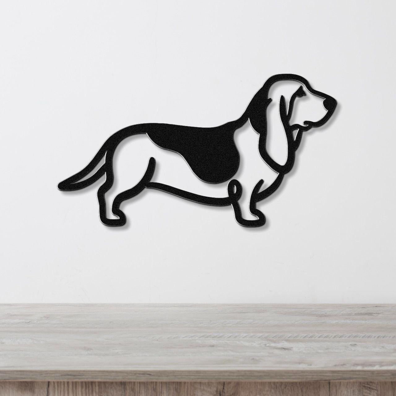 Black metal Basset Hound silhouette wall art with internal cutouts, mounted on a white wall above a light wood surface.
