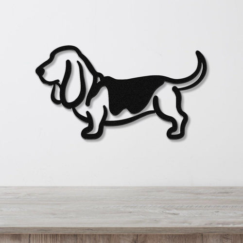 Black metal Basset Hound silhouette wall art with cutout details, mounted on a white wall above a light wood surface.