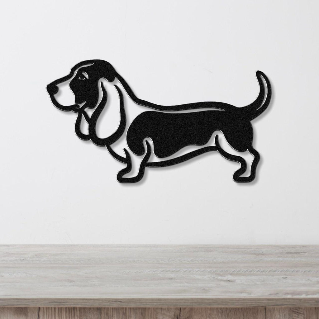 Black metal wall art silhouette of a basset hound, mounted on a white wall above a light wood surface.