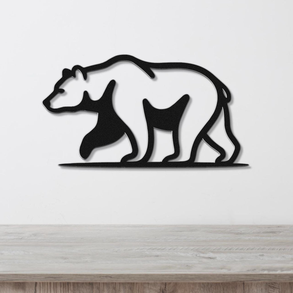 Black metal bear wall art with a silhouette design, mounted on a white wall above a wooden surface.