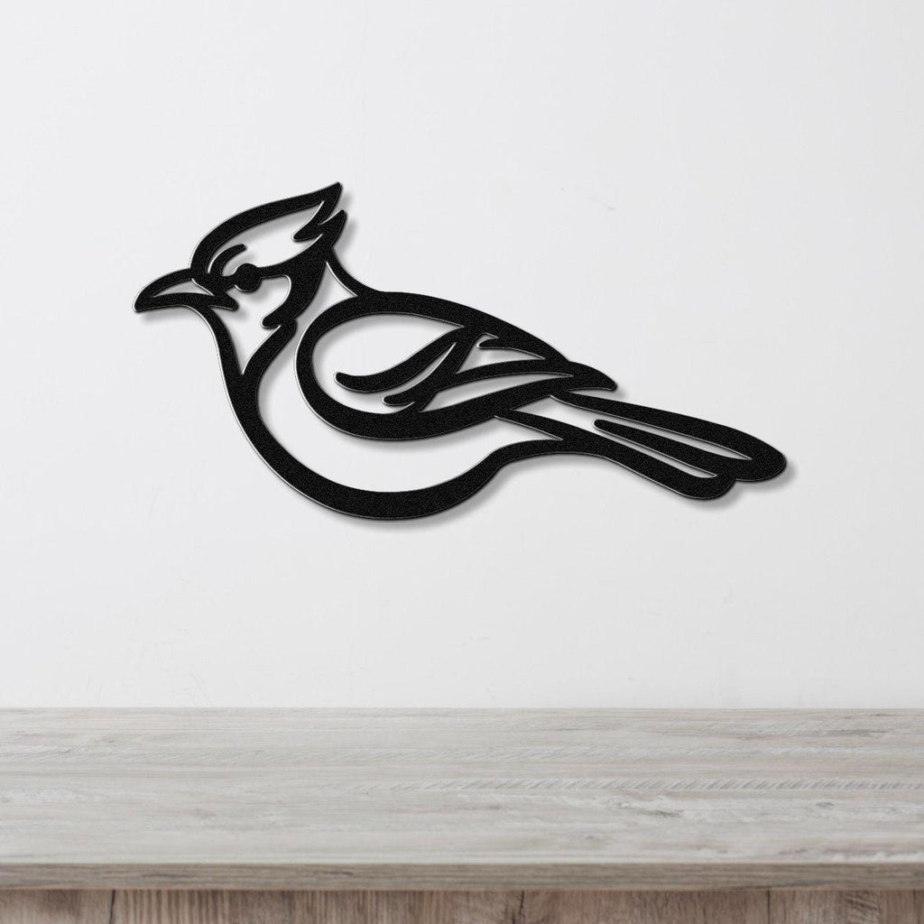 Black metal blue jay wall art with internal feather cutouts, mounted on a white wall above a light wood counter.