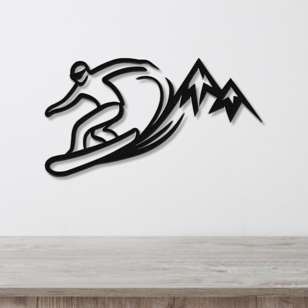 Black metal wall art silhouette of a snowboarder in motion with mountain peaks, mounted on a white wall above a light wood counter.