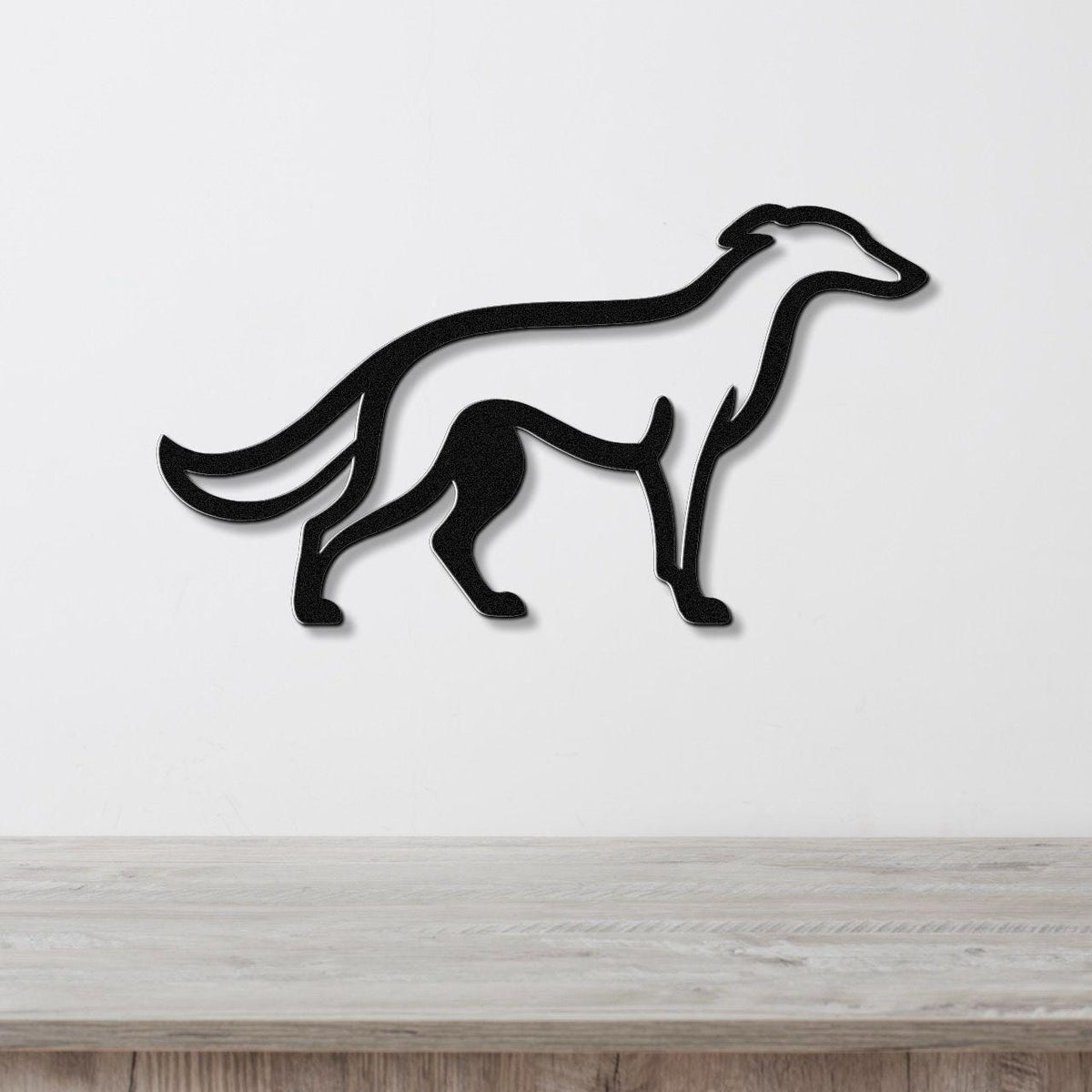 Black metal Borzoi dog wall art silhouette with cutout details, mounted on a white wall above a light wood surface.