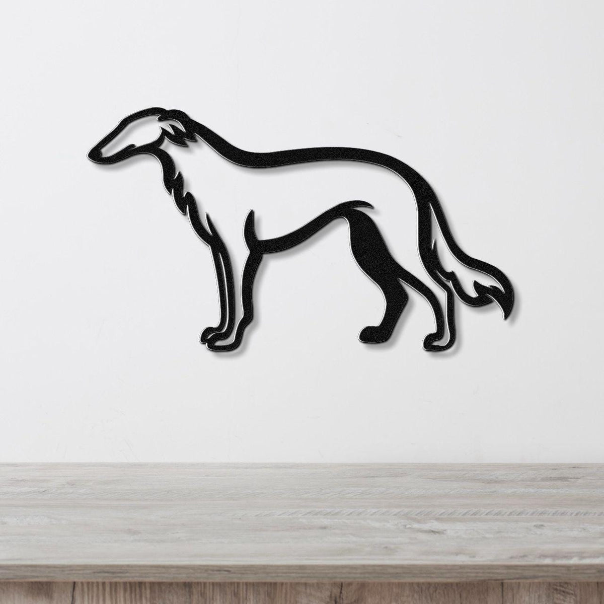 Black metal Borzoi dog wall art silhouette with cutout details, mounted on a white wall above a light wood surface.