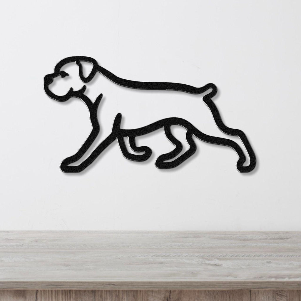 Black metal silhouette wall art of a walking boxer dog, mounted on a white wall above a light wood surface.