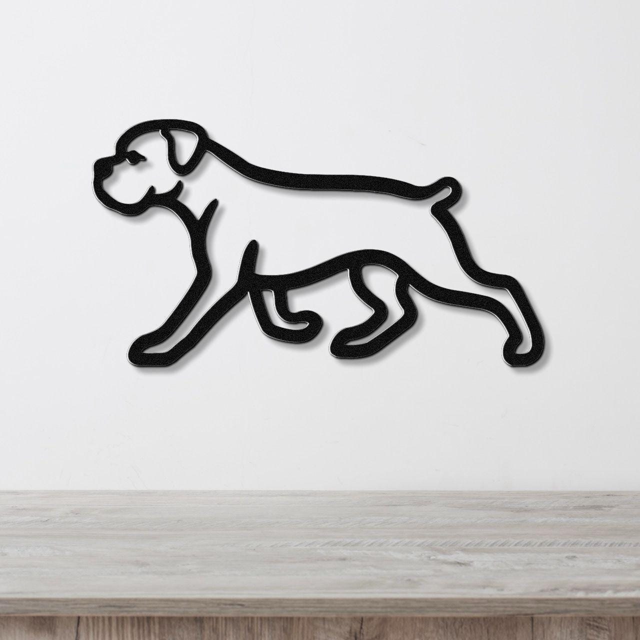Black metal silhouette wall art of a walking boxer dog, mounted on a white wall above a light wood surface.