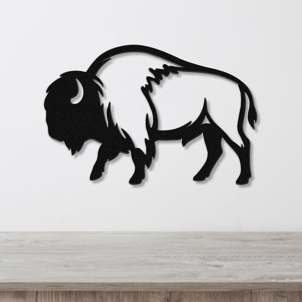 Black metal buffalo wall art with a silhouette cutout design, mounted on a white wall above a light wood countertop.