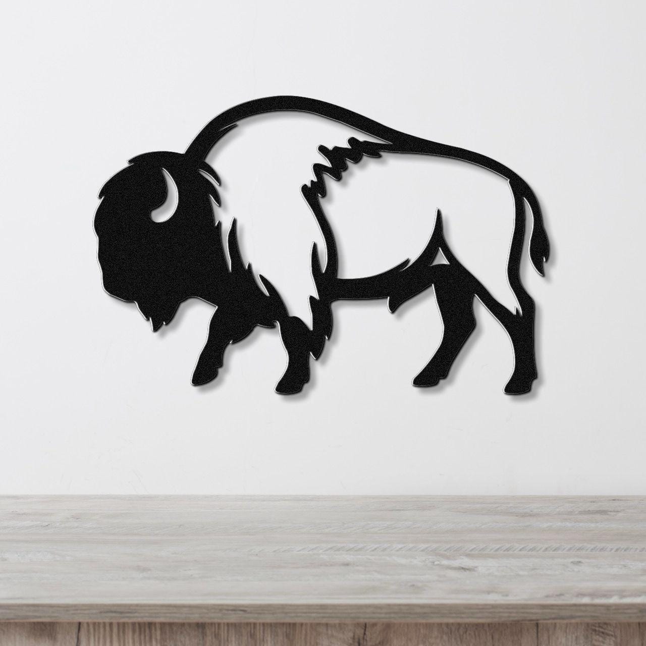 Black metal buffalo wall art with a silhouette cutout design, mounted on a white wall above a light wood countertop.