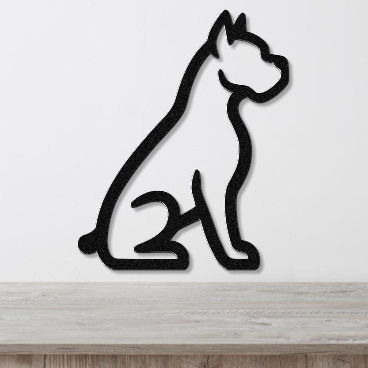 Black metal wall art featuring a bold silhouette of a sitting boxer dog, mounted on a white wall above a light wood surface.