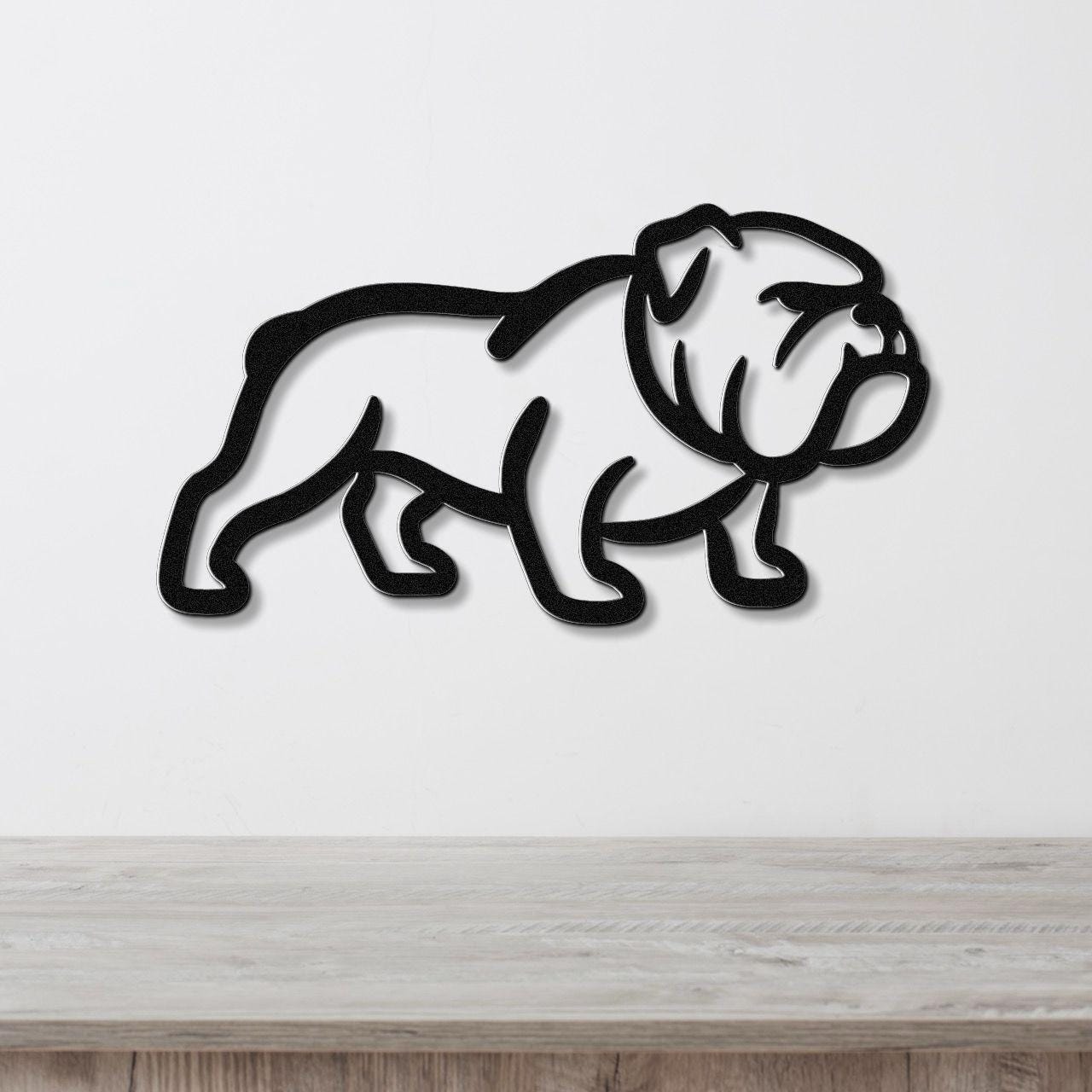 Black metal bulldog wall art with a bold silhouette and internal cutout details, mounted on a white wall above a light wood counter.