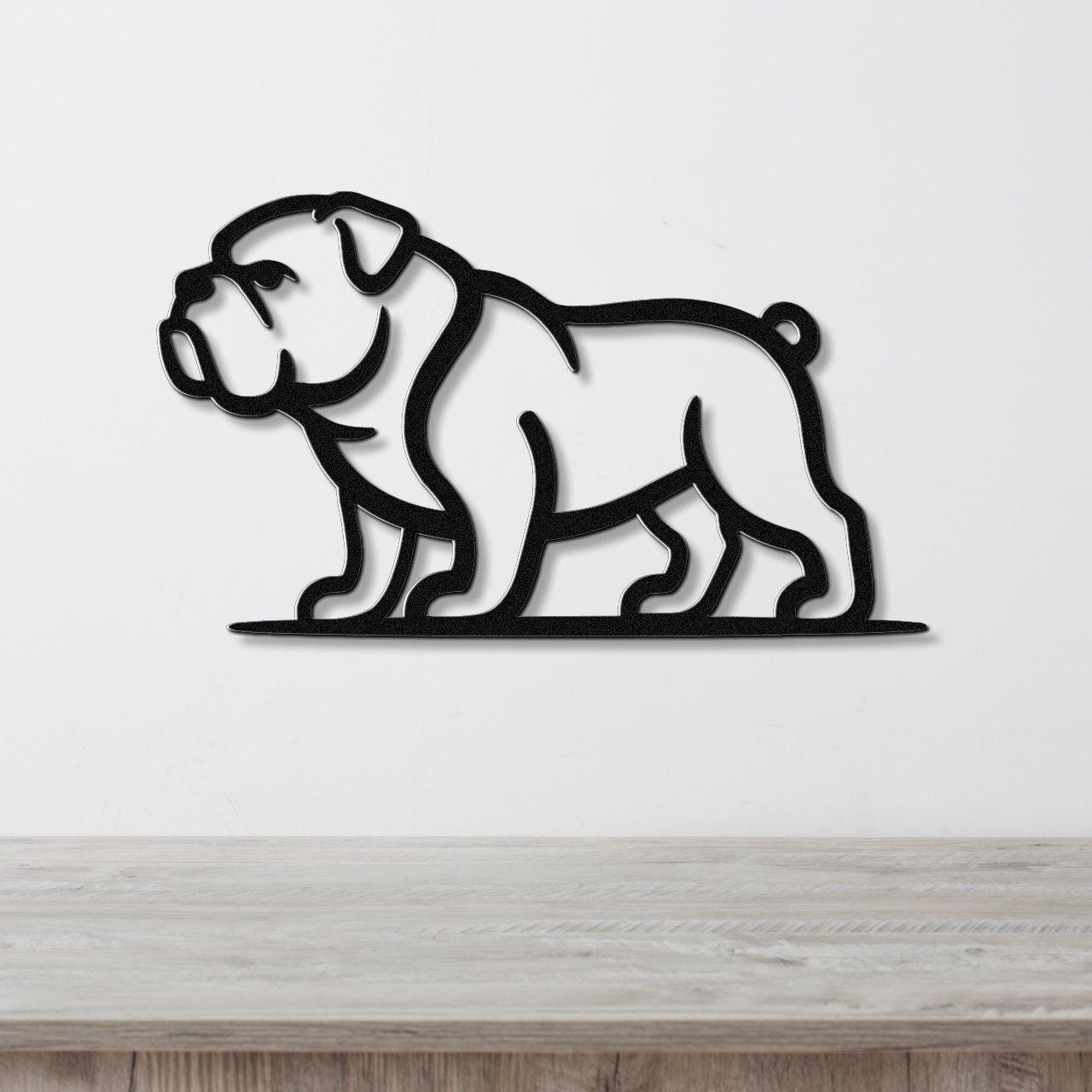Black metal bulldog wall art with a minimalist silhouette design, mounted on a white wall above a light wood surface.