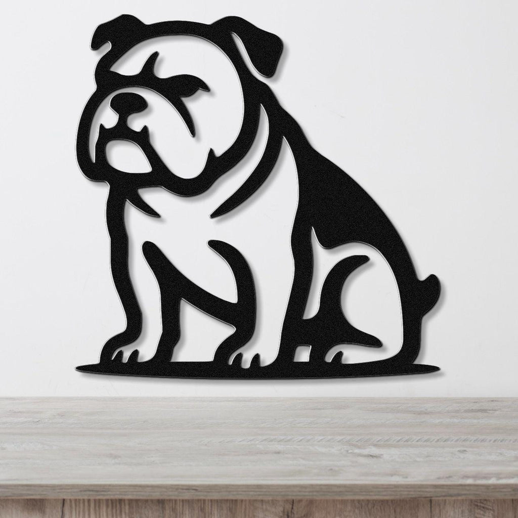 Black metal bulldog wall art with a bold silhouette and internal cutouts, mounted on a white wall above a wooden surface.