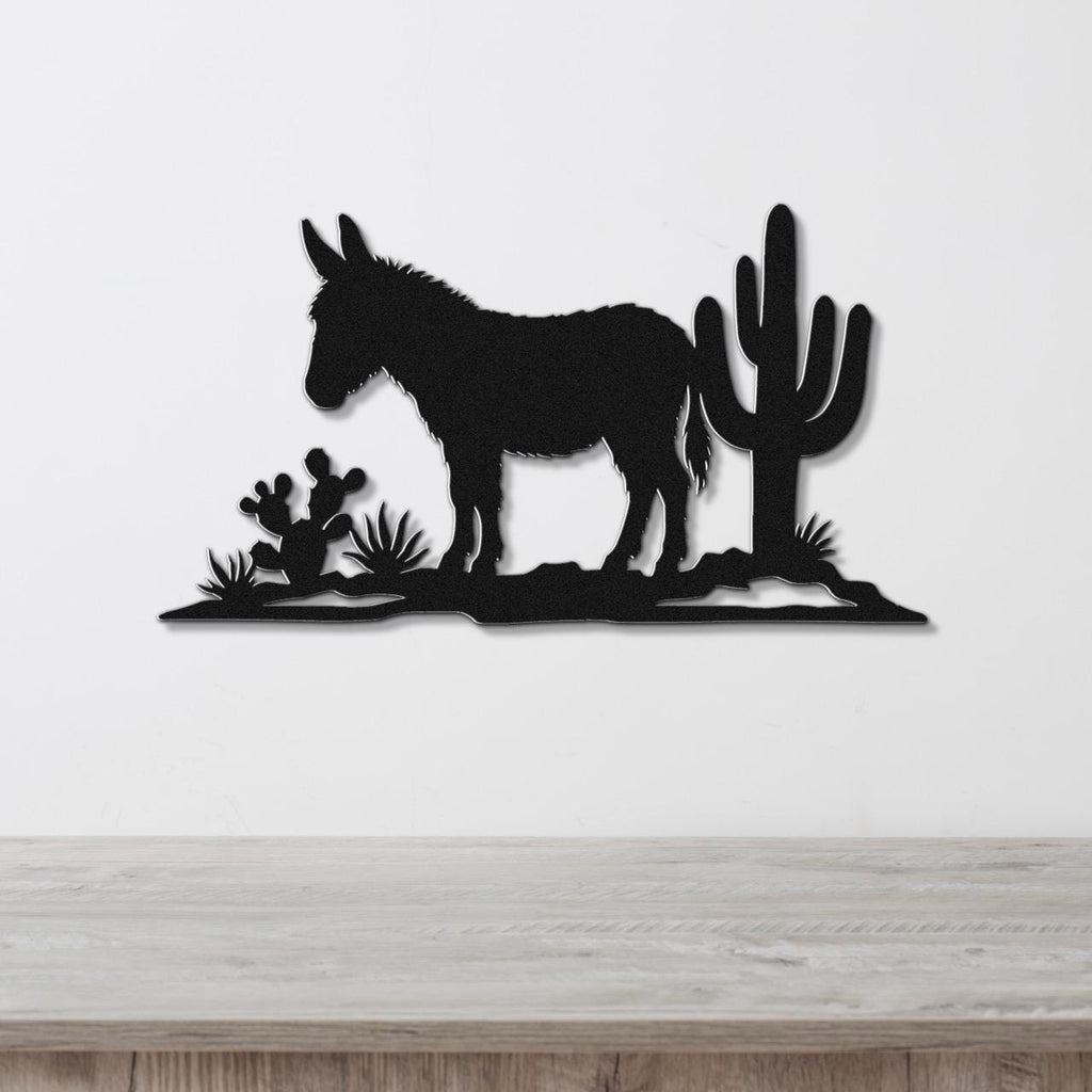 Black metal wall art silhouette of a burro and cacti, mounted on a white wall above a wooden surface.