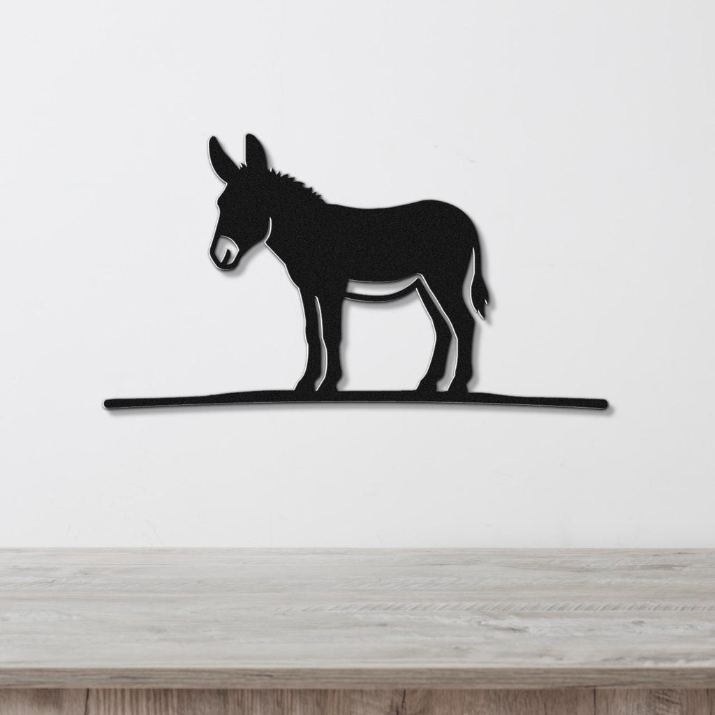 Black metal donkey wall art silhouette with a long horizontal base, mounted on a white wall above a wooden surface.