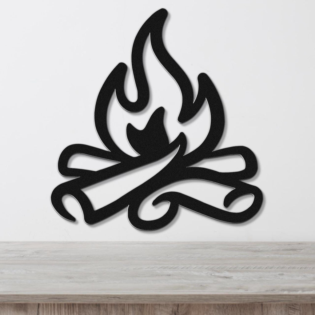 Black metal wall art in a flame and log silhouette design, mounted on a white wall above a light wood surface.