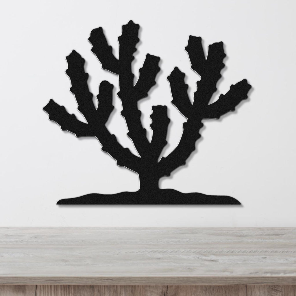 Black metal wall art in a cholla cactus silhouette with branching cutouts, mounted on a white wall above a light wood counter.