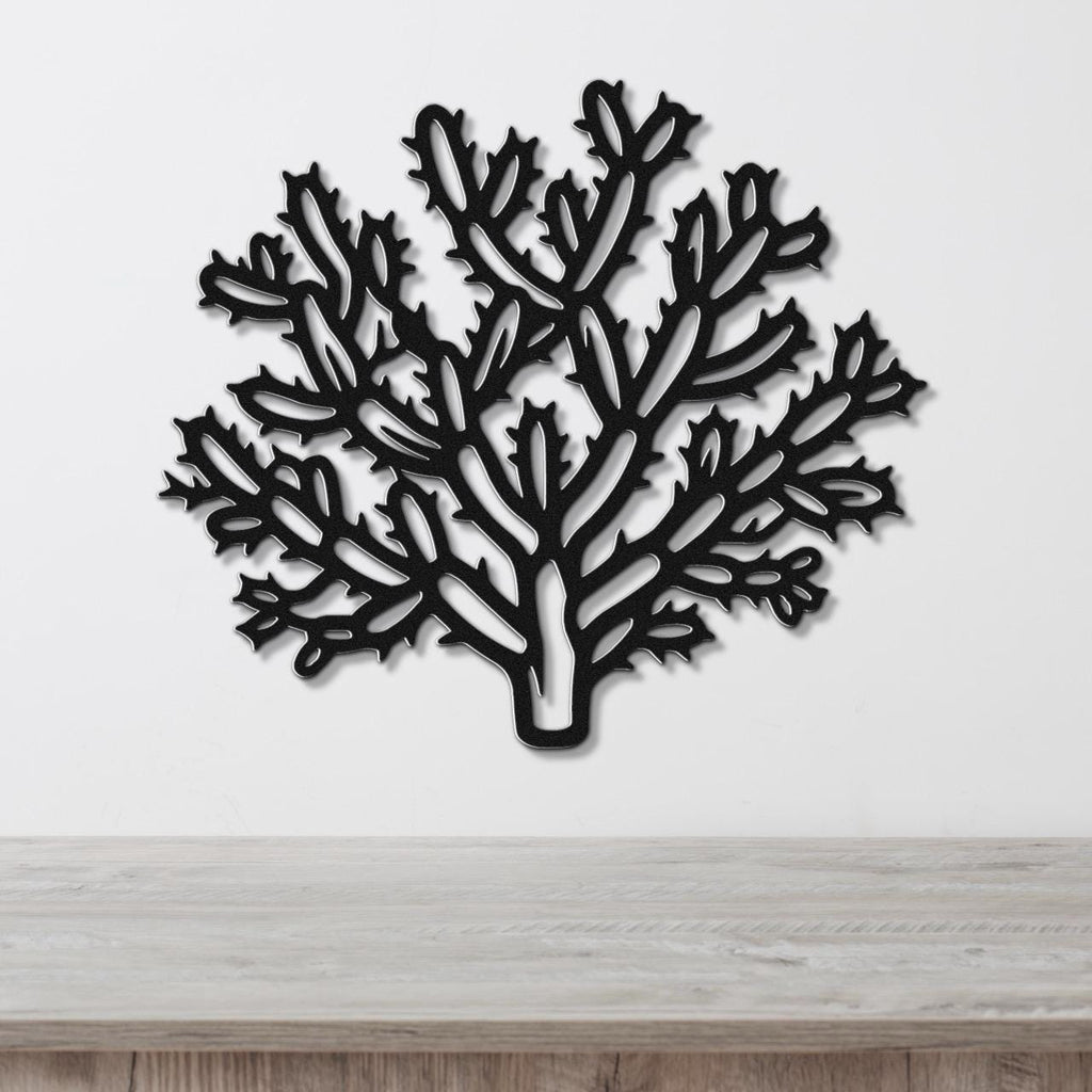 Black metal wall art cutout of a cholla cactus with branching arms and spines, mounted on a white wall above a light wood surface.