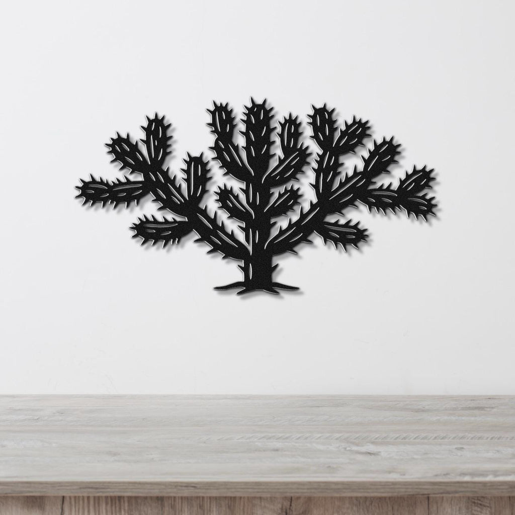 Black metal Cholla cactus wall art with detailed spines and branching cutouts, mounted on a white wall above a light wood counter.