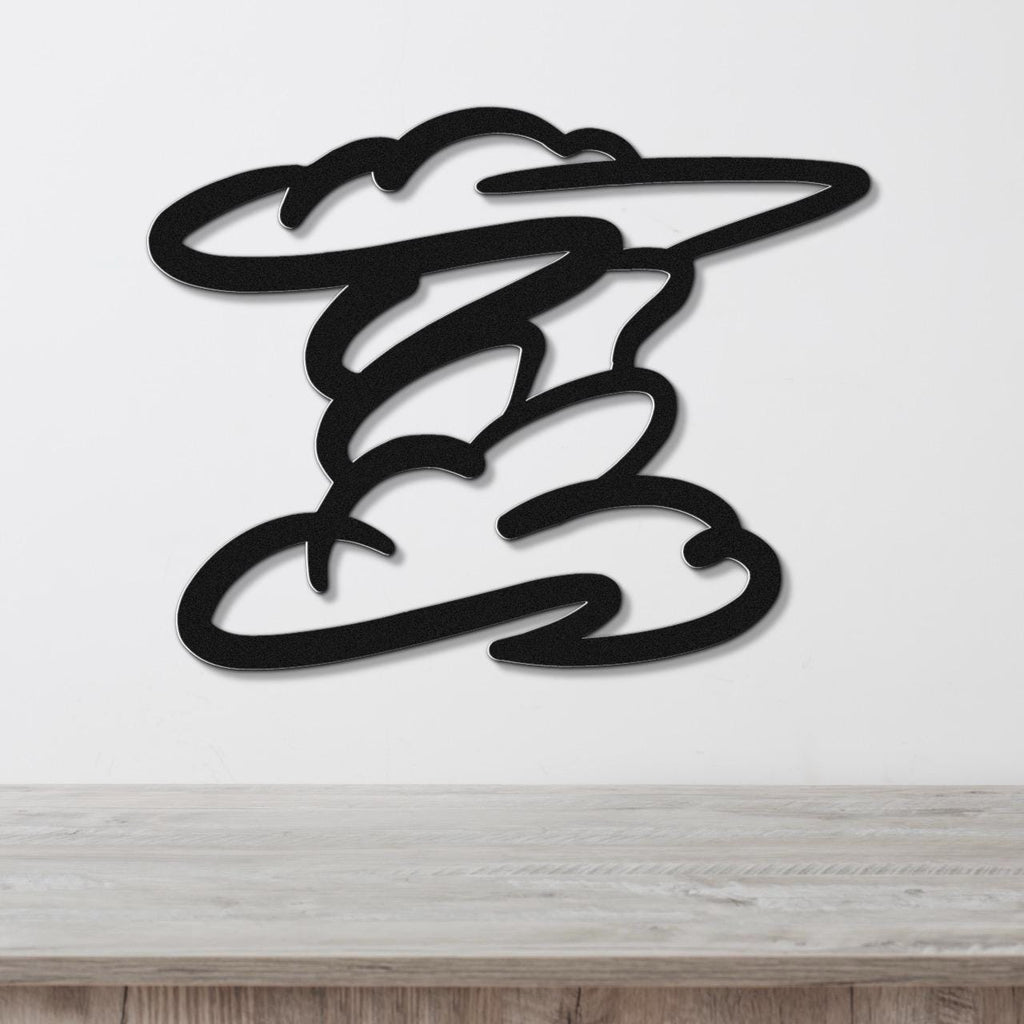 Black metal wall art in a cloud silhouette design with layered cutouts, mounted on a white wall above a light wood surface.