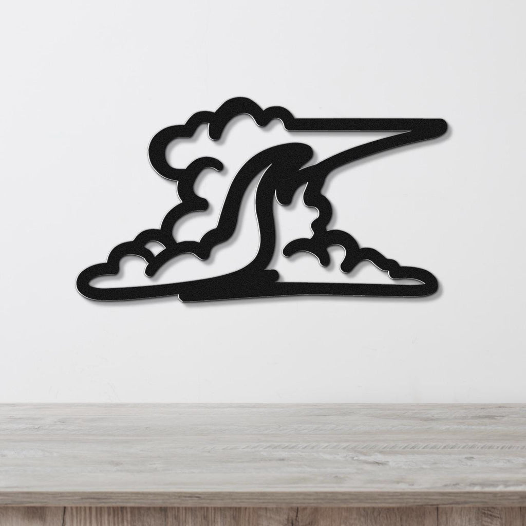 Black metal wall art cutout of a cloud with a wave-like shape, mounted on a white wall above a wooden surface.