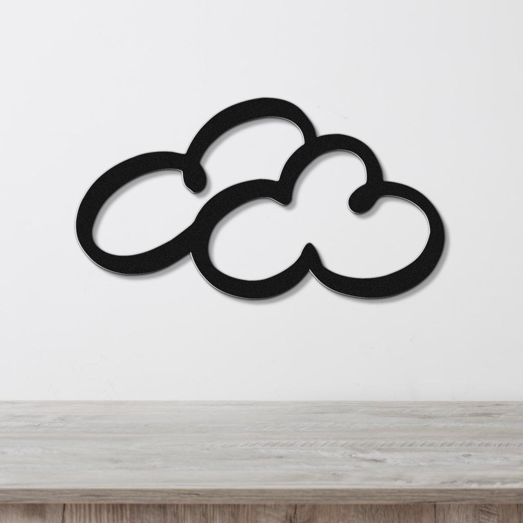 Black metal cloud-shaped wall art with cutout design, mounted on a white wall above a light wood surface.