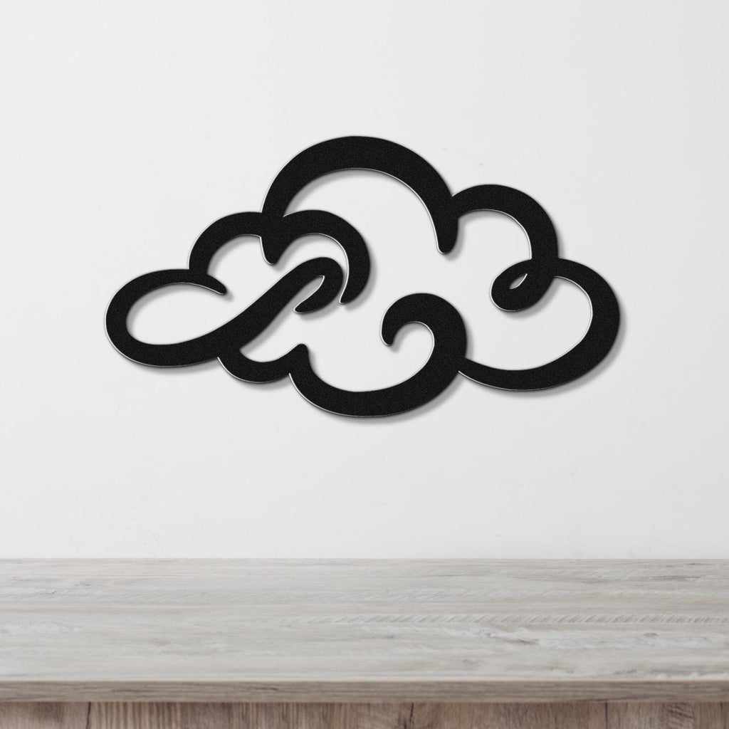 Black metal cloud wall art with swirling cutout design, mounted on a white wall above a light wood surface.