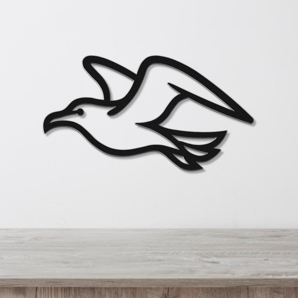 Black metal seagull wall art with wing and tail cutouts, mounted on a white wall above a light wood counter.