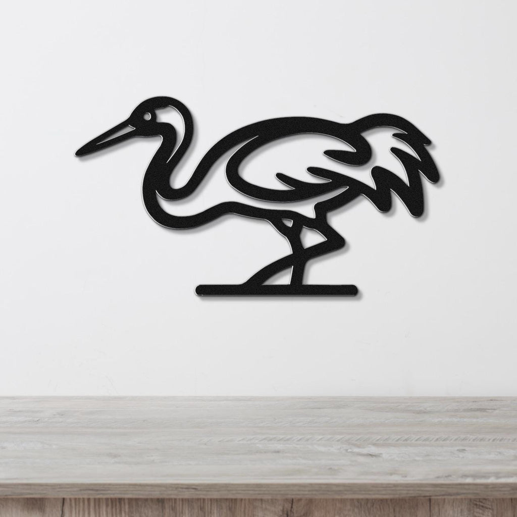 Black metal crane wall art with a cutout silhouette design, mounted on a white wall above a light wood surface.