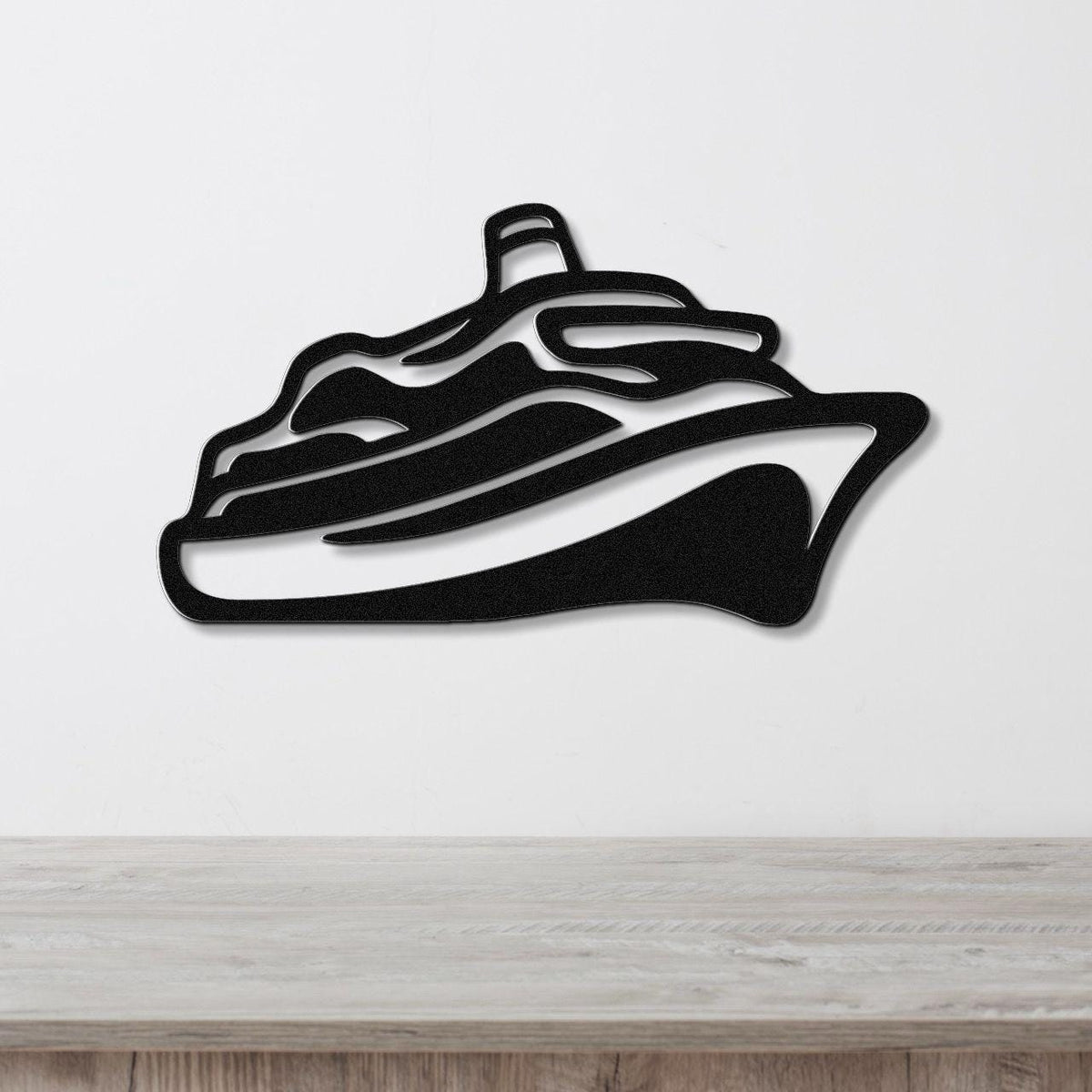 Black metal cruise ship wall art with layered silhouette cutouts, mounted on a white wall above a light wood counter.
