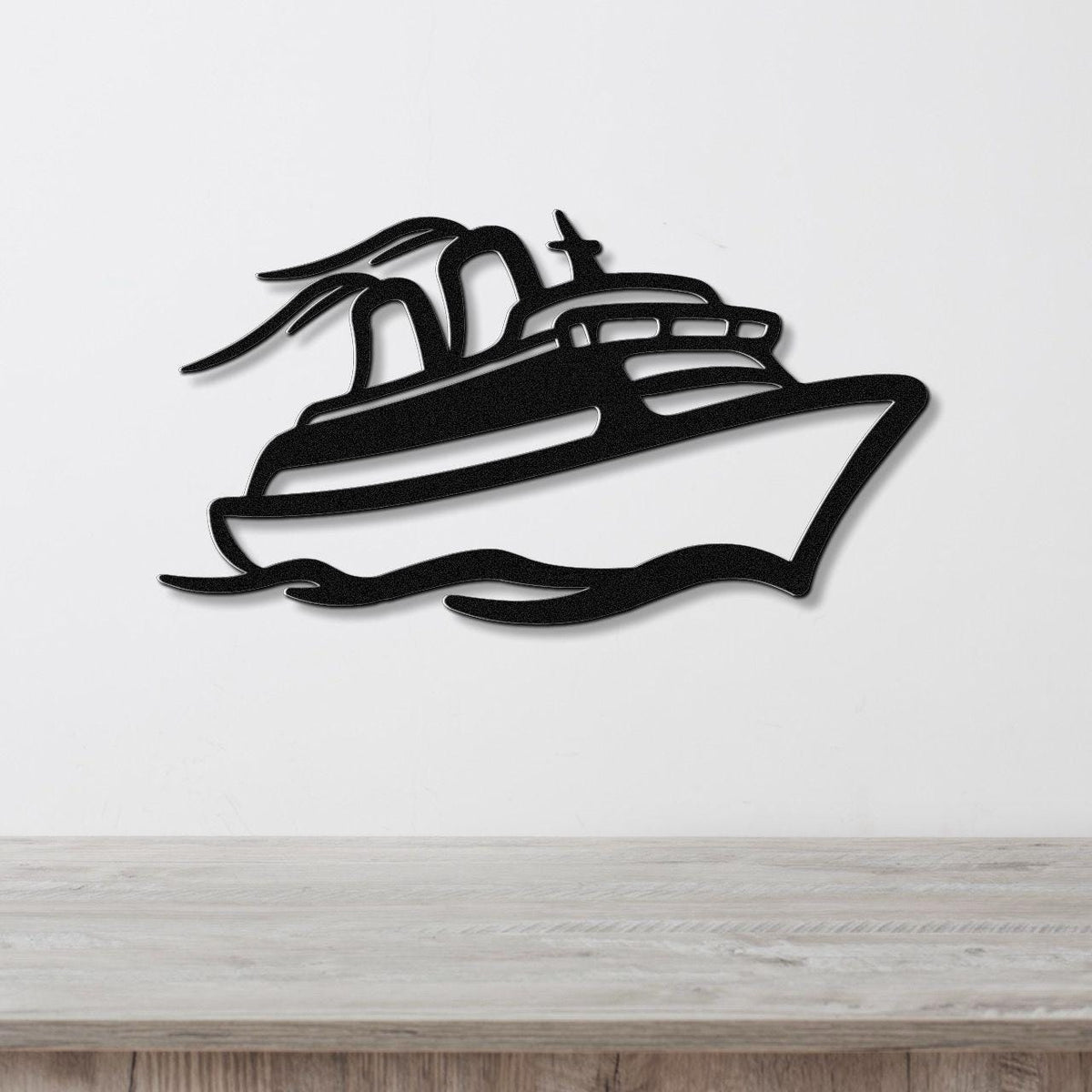 Black metal wall art cutout of a cruise ship with motion lines, mounted on a white wall above a light wood counter.