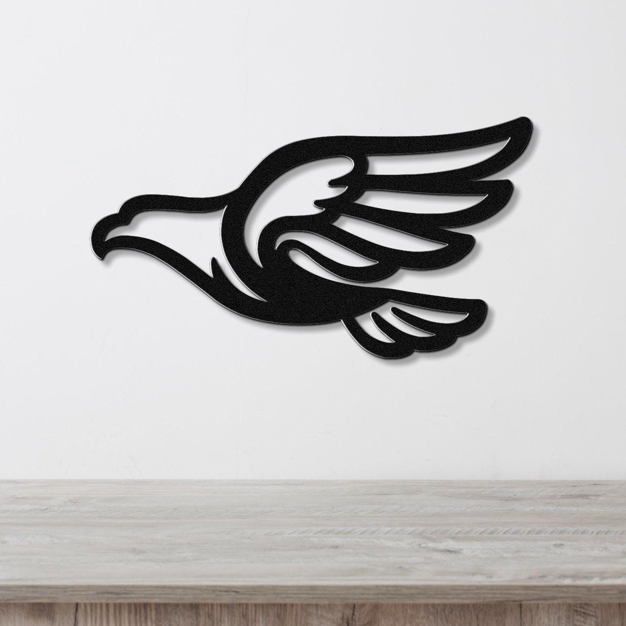 Black metal eagle wall art with wing and tail cutouts, mounted on a white wall above a light wood counter.