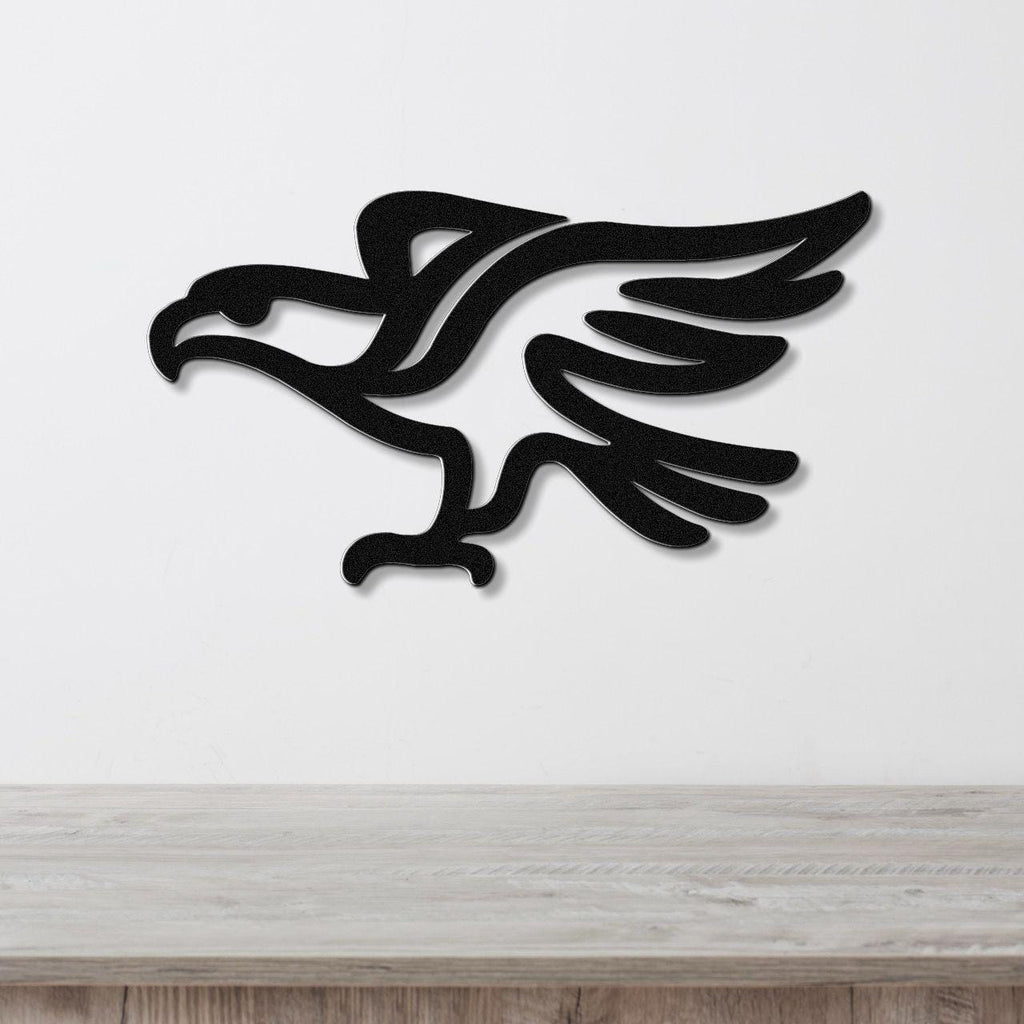 Black metal eagle wall art with a bold silhouette and cutout wing details, mounted on a white wall above a light wood counter.