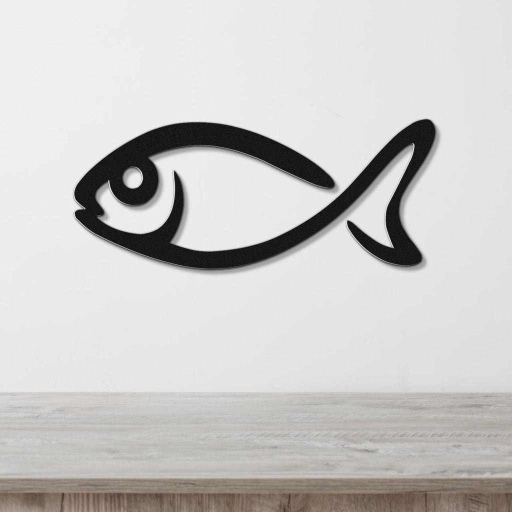 Black metal fish wall art with a bold silhouette design, mounted on a white wall above a light wood surface.