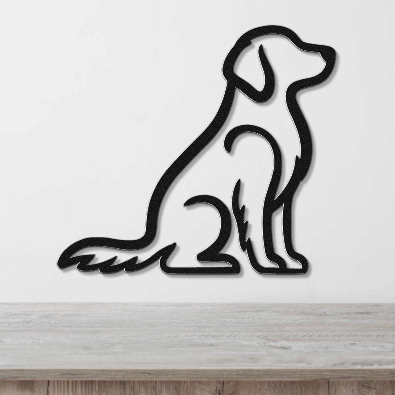 Black metal wall art in the silhouette of a sitting dog, mounted on a white wall above a light wood surface.