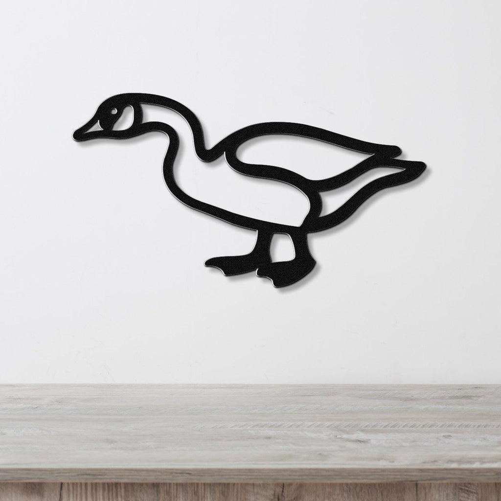 Black metal goose wall art silhouette with cutout details, mounted on a white wall above a light wood surface.